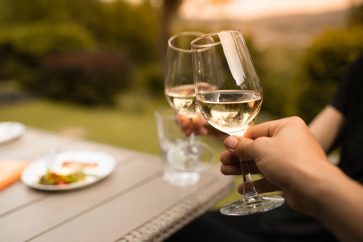 Pareja brindando con copas de vino blanco