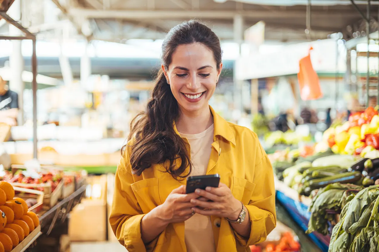 Mujer usando su celular en el mercado