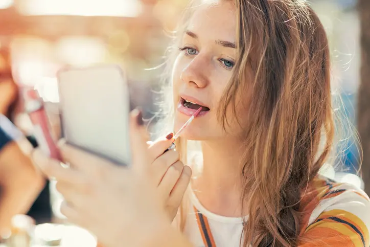 joven mujer maquillandose al aire libre en una tarde de verano