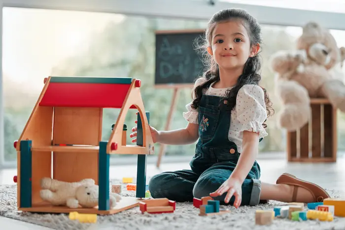 niña feliz jugando con una casita de muñecas