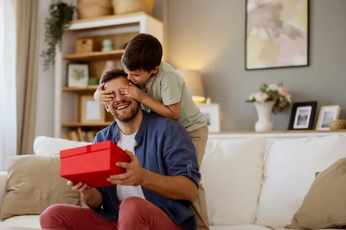 hijo sorprendiendo a su papa con un regalo por su dia