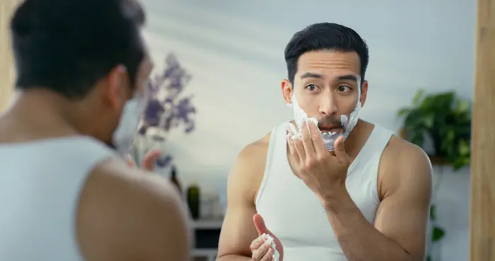 hombre afeitandose la barba en su baño