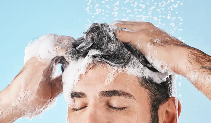 hombre lavando su pelo con shampoo para caida del cabello
