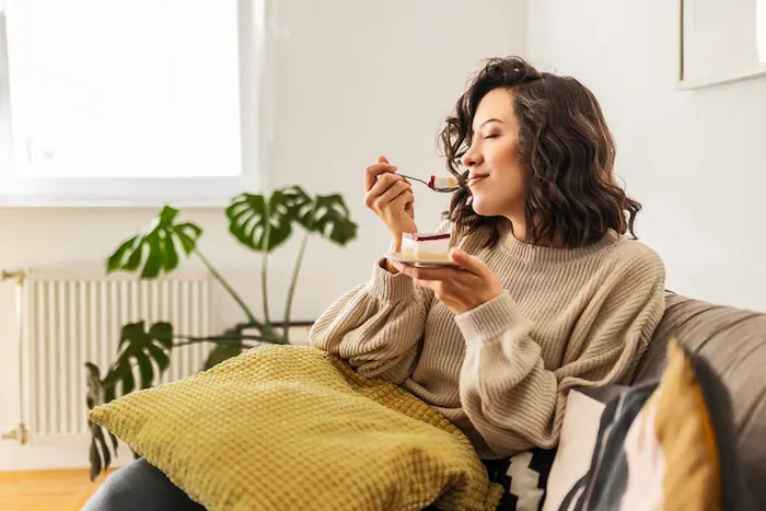 mujer feliz y sonriente comiendo pastel
