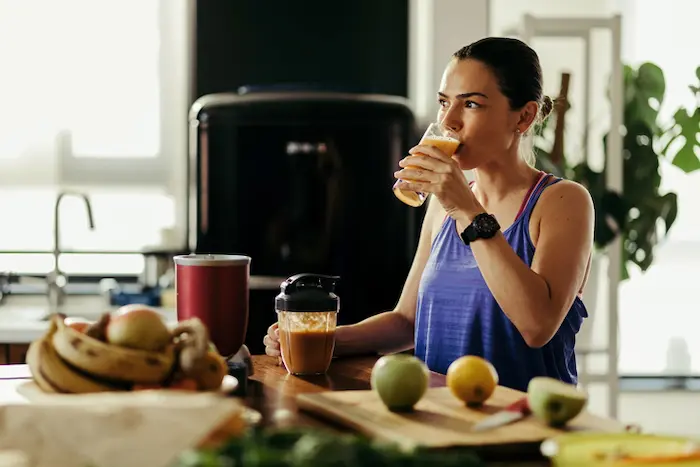 mujer tomando un licuado de aguas frescas naturales