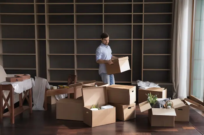joven ordenando cajas de electrodomésticos para primer hogar