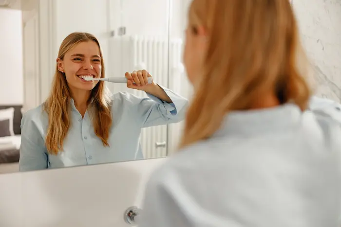 mujer con cepillo de dientes electrico